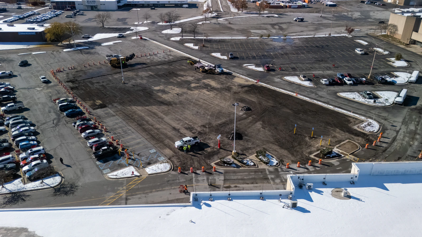 Overhead drone view of a Target store parking lot mid-repair with old pavement removed and crews preparing the base