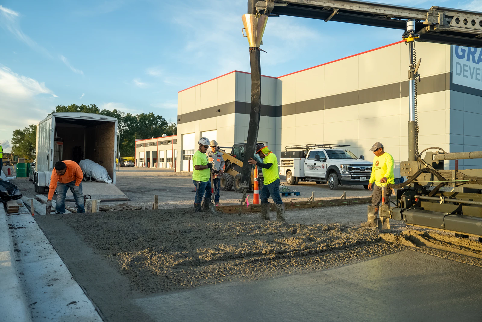 Advantage Paving crew placing concrete from a pump truck boom for a new dealership lot slab